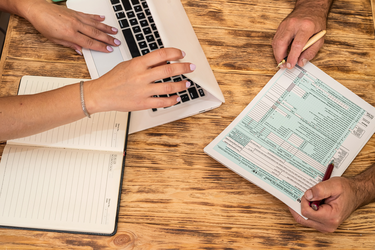 Two accountants completing tax forms side by side, illustrating the collaborative process of Streamlined Filing Procedures.
